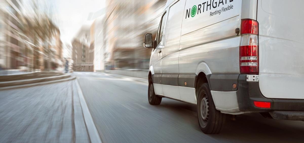 A fast moving white van on a bright street with high buildings. Motion blurred background.