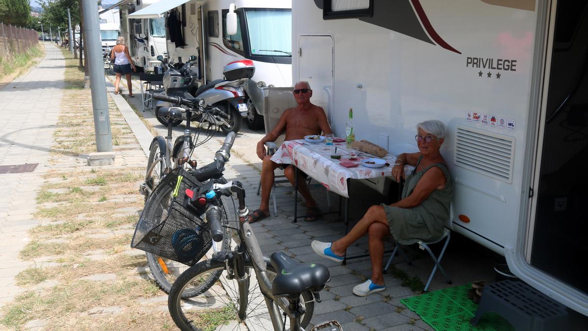 Una parella dinant en un carrer en una terrassa improvisada a la via pública en una zona on aparquen caravanes