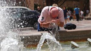 Un hombre se refresca en una fuente durante una ola de calor.