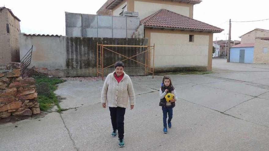 Una niña y su abuela caminan delante del cementerio de Vecilla donde se ubican los nichos/