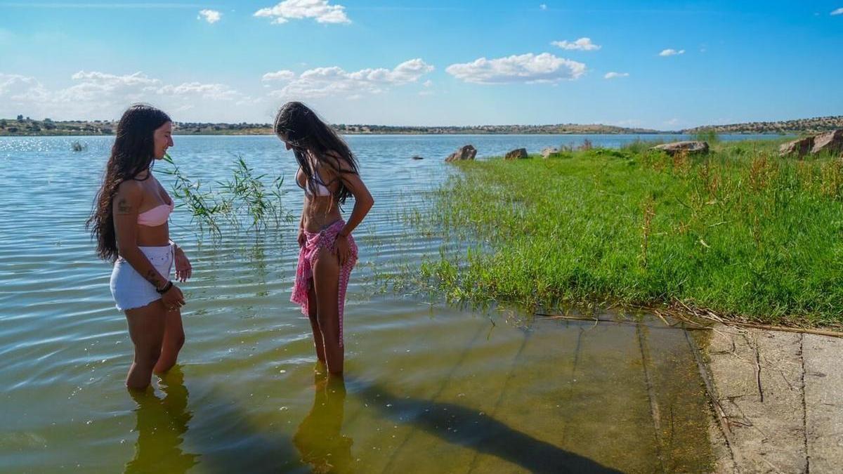 Dos jóvenes conversan en la orilla del embalse de La Colada, en El Viso.