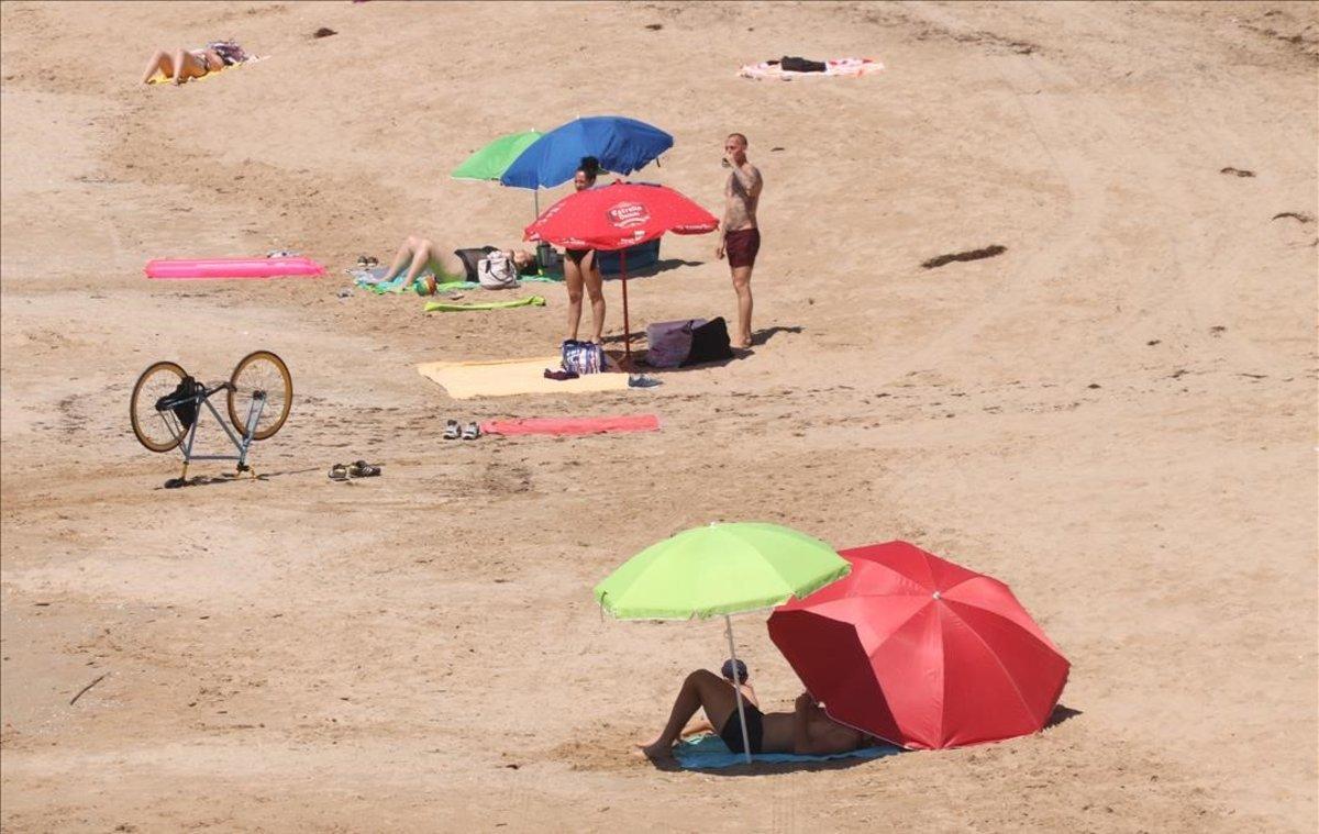 Gente tomando el sol en la playa del Miracle, en Tarragona.