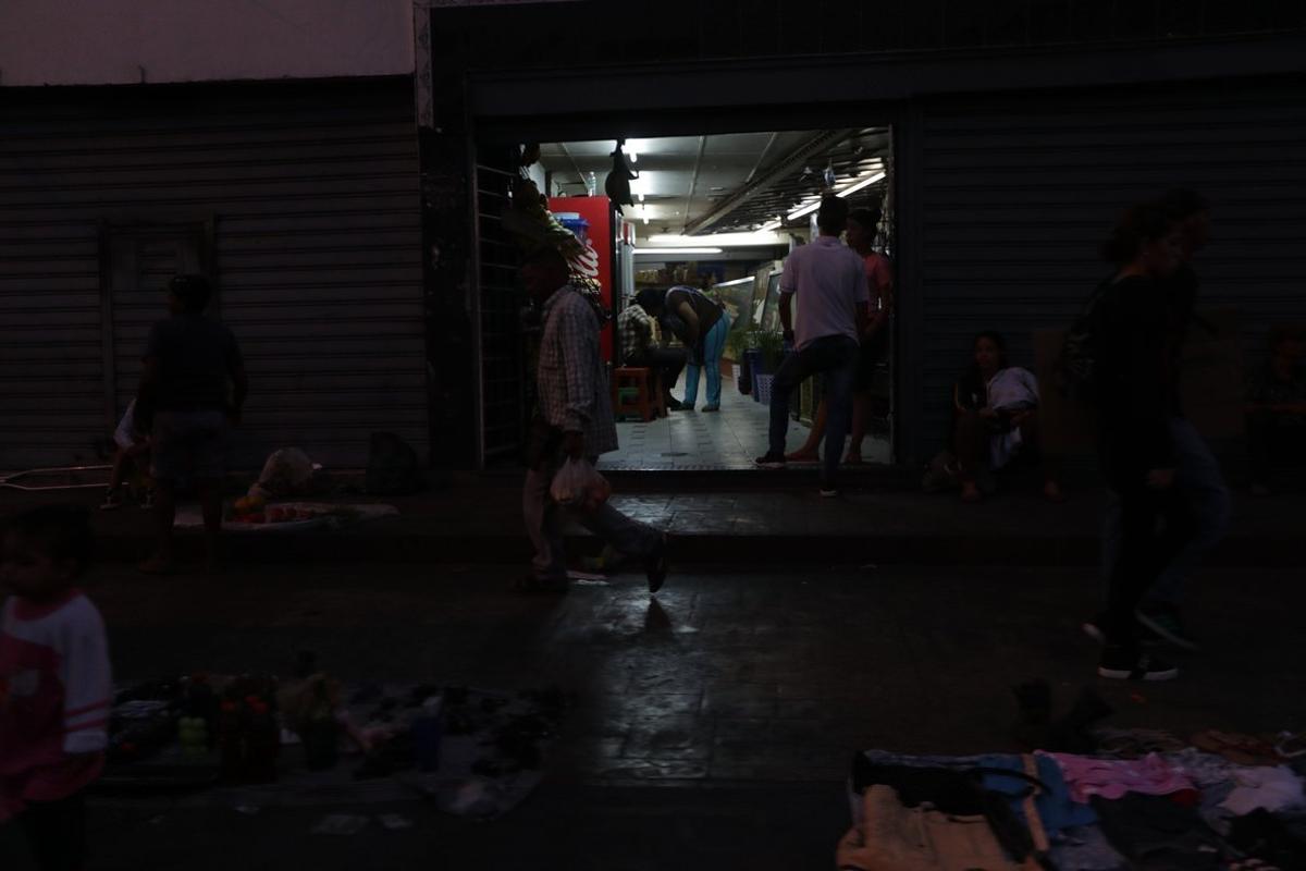 ACOMPANA CRONICA VENEZUELA CRISIS   AME2132  CARACAS  VENEZUELA   28 03 2019 - Comerciantes abren sus locales mientras la calle permanece a oscuras por la falta de fluido electrico en la via publica hoy  jueves en Caracas  Con una bolsa de hielo y otra de pan  el abogado Amos Martinez sale cual cazafortunas de una tienda en Caracas  Consiguio su pequeno botin tras sortear el apagon que desde el lunes mantiene su casa a oscuras y practicamente paralizada la ya deprimida actividad comercial en Venezuela  EFE  Rayner Pena ACOMPANA CRONICA VENEZUELA CRISIS