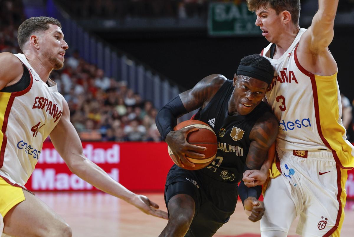 El base de la selección alemana de baloncesto Dennis Schroeder (c) trata de superar al español Sergio de Larrea (d), durante el partido amistoso que España y Alemania disputan este jueves en el Madrid Arena.