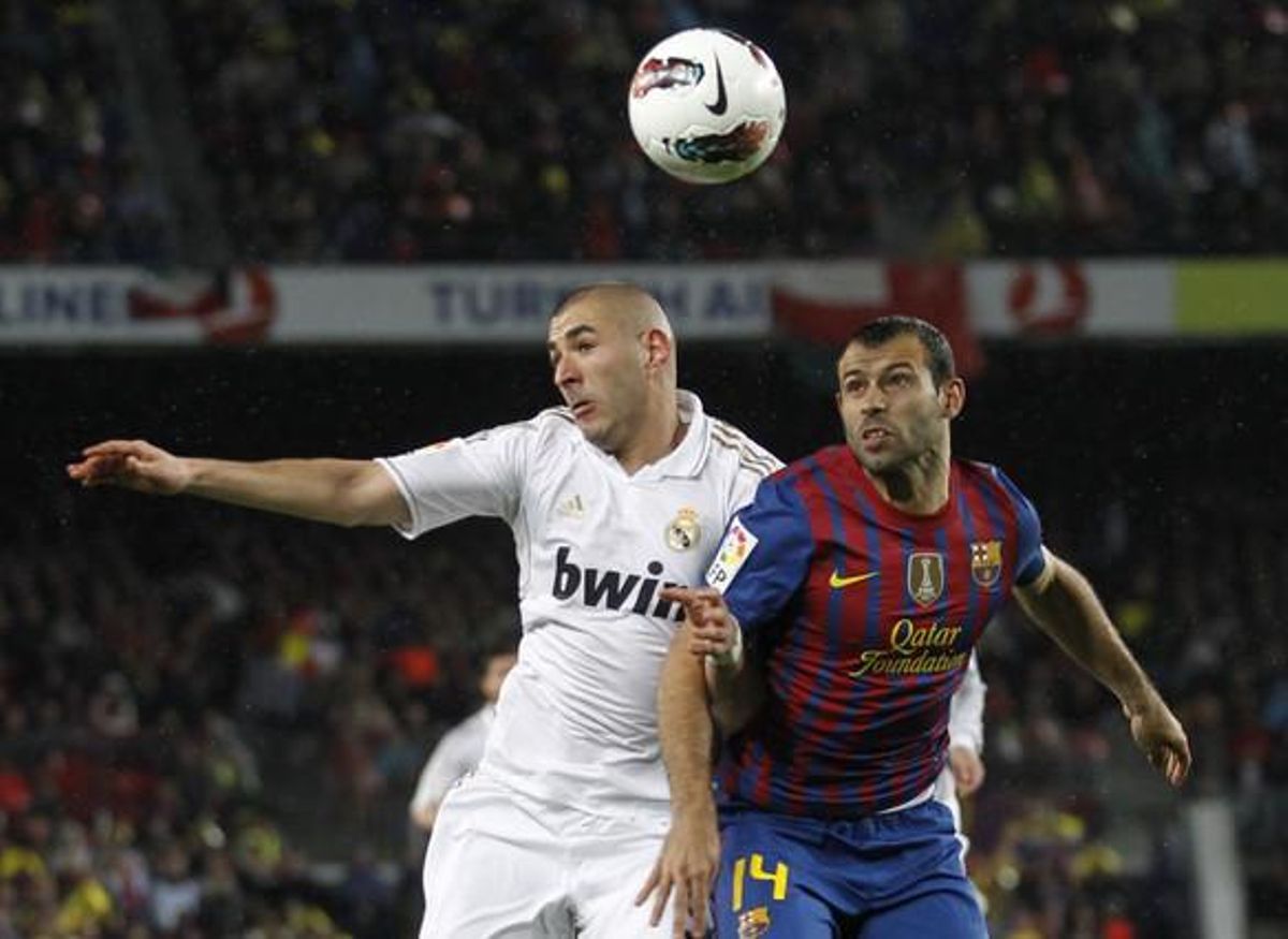 Javier Mascherano es disputa una pilota amb Karim Benzema.