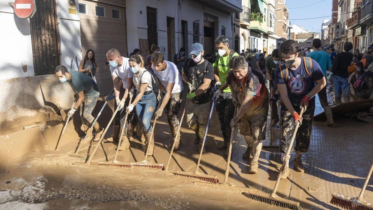 Vecinos y voluntarios de Paiporta retiran el lodo acumulado en una de las calles.