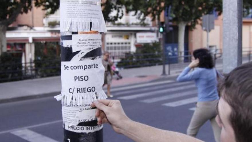 Un joven observa un anuncio pegado en una farola de la ciudad.