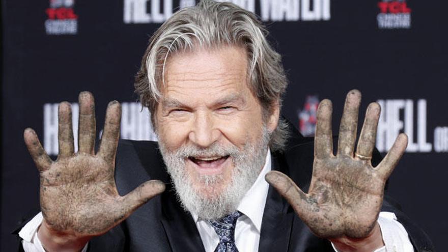 El actor Jeff Bridges muestra sus manos tras dejar sus huellas.