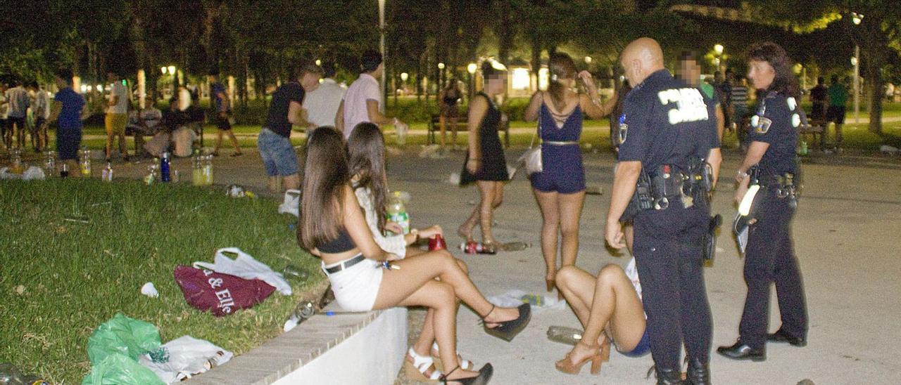 Jóvenes de fiesta en un parque de la playa de Gandia, ante agentes de la Policía Local, en una imagen de archivo. | T. Á. C.