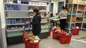 Archivo - Una persona selecciona los productos para su la cesta de compra en el interior del economato solidario de Cáritas situado en la calle Bravo Murillo de Madrid