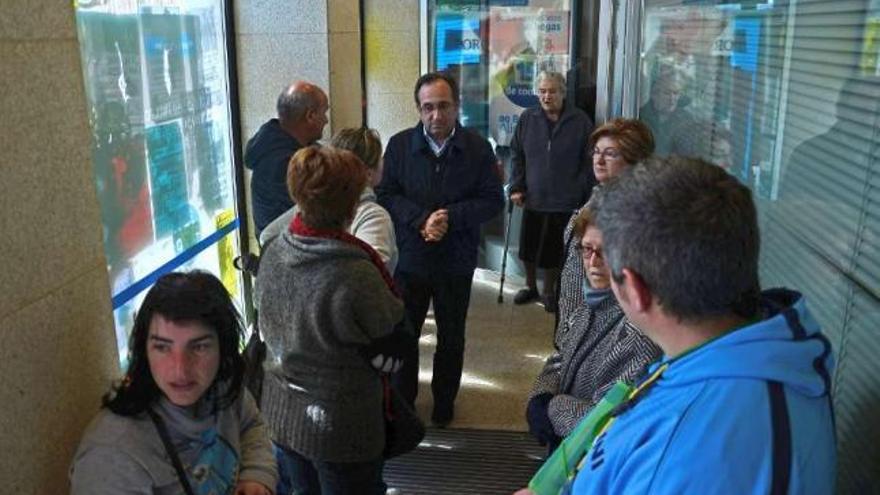 Afectados de las preferentes charlan con el alcalde den el pasillo de acceso a la oficina de NCG  // G.N.