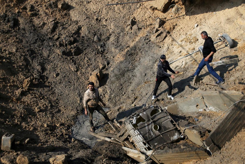 Palestinians inspect the site of an Israeli air ...