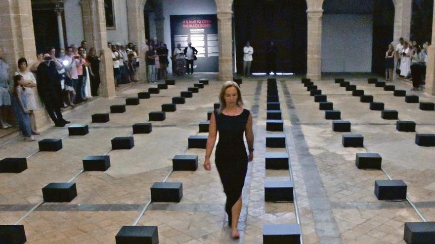 La artista griega Danae Stratou pasa junto a las cajas negras de su exposición.