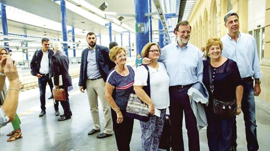 Rajoy y Albiol (dcha.) se fotografían con seguidores en la estación de Lérida. Al fondo (izq.), Sánchez. // Efe