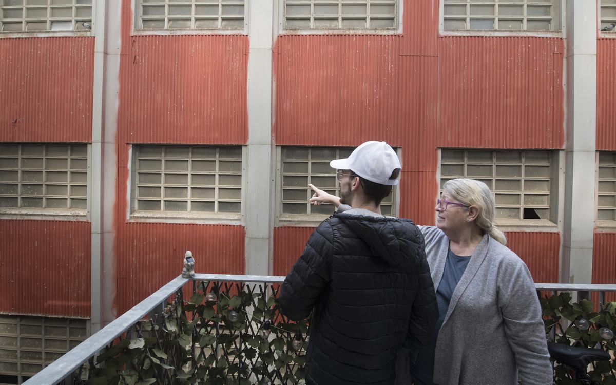 la señora Montse observa la pared de amianto, tintado en los últimos meses, de la nave que tiene frente a su piso en la calle Pallars a la espera de una solución