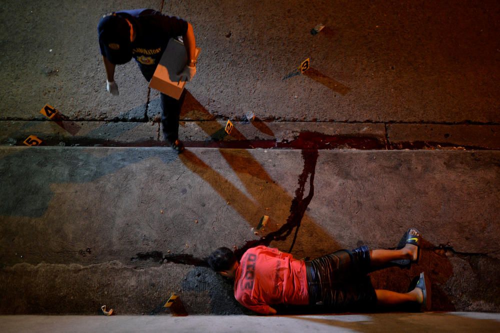 A police investigator walks next to the body of ...