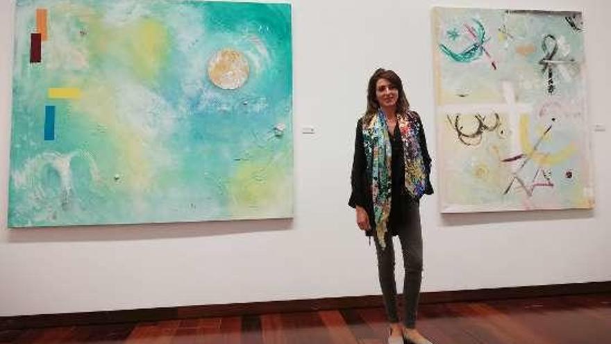 La artista Sara Castro, entre dos de las obras expuestas en Vigo.