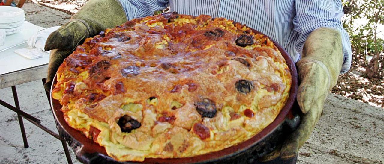 El tradicional plato de arroz con costra donde no falta el embutido y su dorada cobertura, y firmas presentadas en el PROP de Orihuela por ACMO este viernes. | INFORMACIÓN