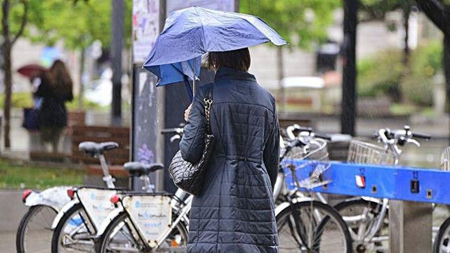 Una mujer se protege de la lluvia en una calle de A Coruña.