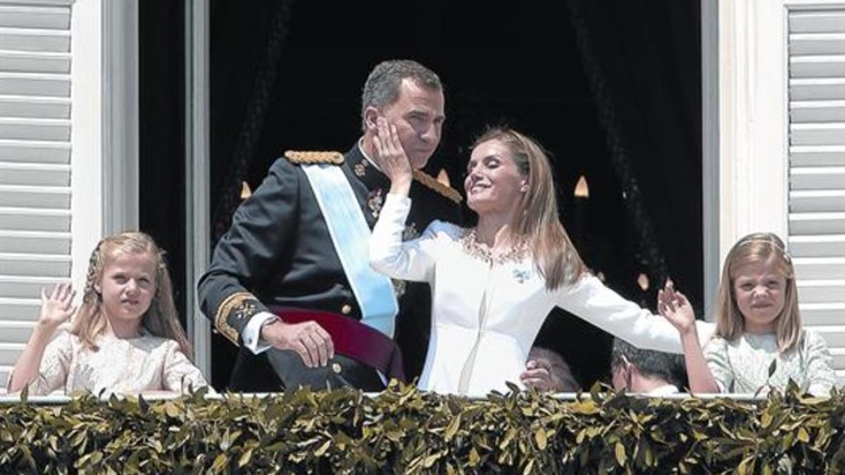 Los reyes Felipe  y Letizia, la princesa Leonor y la infanta Sofía saludan desde el balcón del Palacio Real, en Madrid.