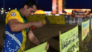 Un partidario de Rousseff clava un cartel en las afueras del senado brasileño.