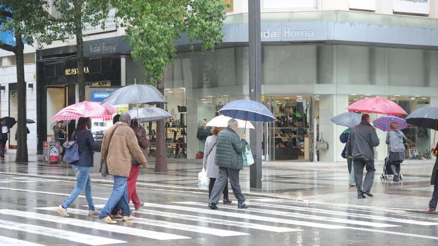 Peatones se protegen de la lluvia en Gran Vía.