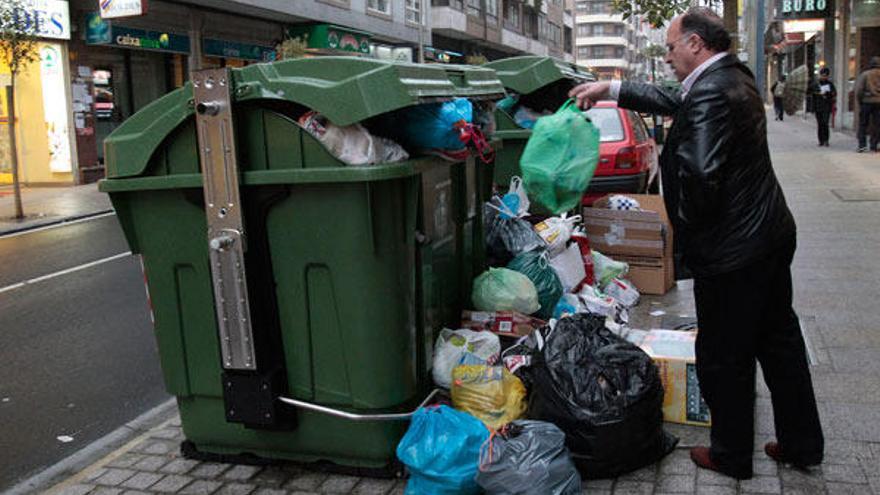 Un hombre deposita unas bolsas de basura en un contenedor de la ciudad
