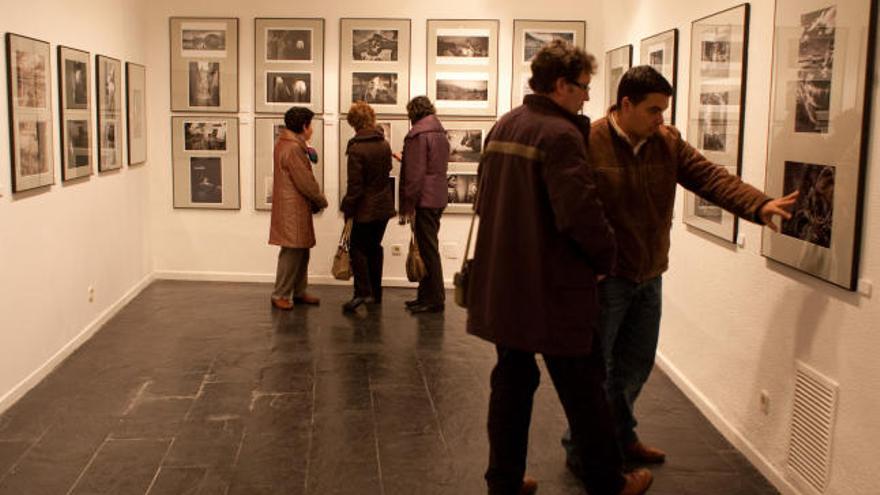 Varias personas observan las fotografías expuestas en la Obra Social de Caja España.