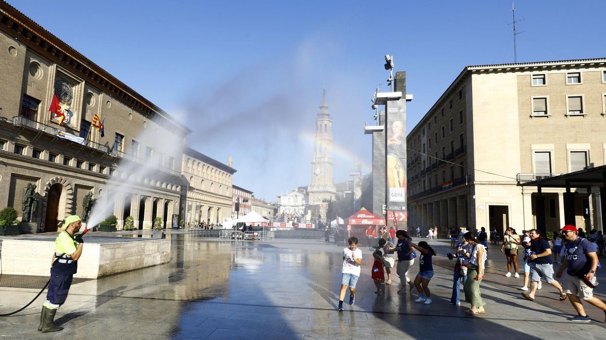 Un operario refresca con la manguera a un grupo de personas en la plaza del Pilar de Zaragoza, este fin de semana.