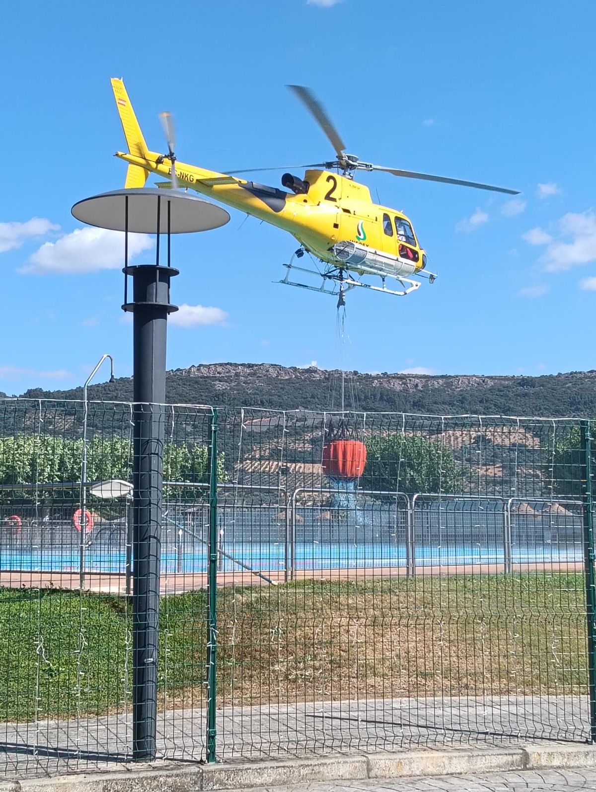Un helicóptero se abastece de agua de la piscina municipal de Herrera del Duque.