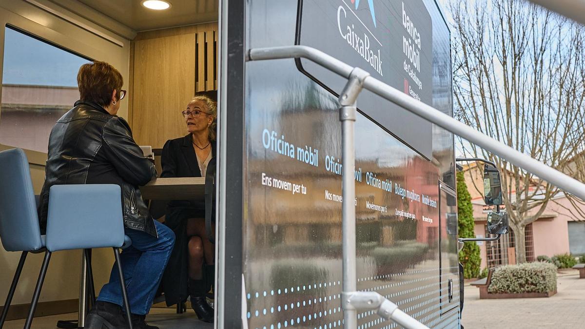 Una clienta es atendida en el interior de la unidad de banca móvil en Santa Eulàlia Riuprimer.