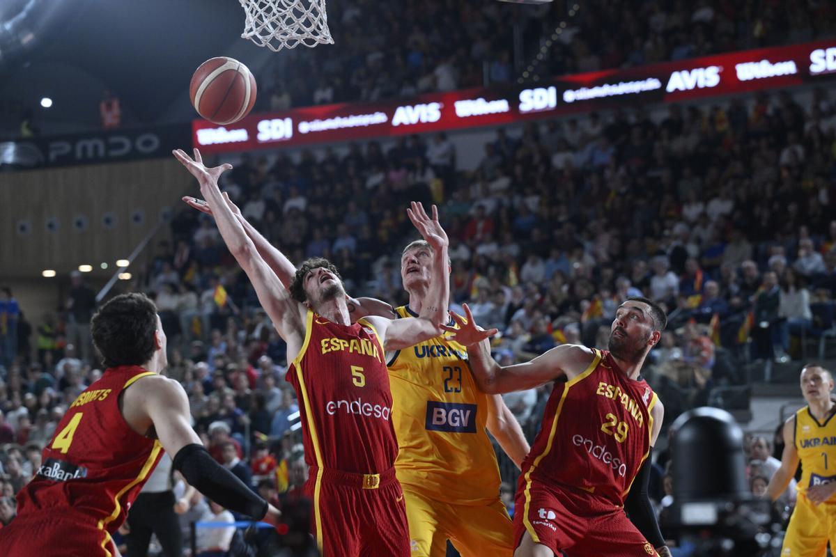 OVIEDO, 02/03/2026.- El pívot de la selección ucraniana Artem Pustovyi (c) pelea un balón con Oriol Paulí (2-i) y Pierre Oriola (2-d), ambos de España, durante el partido de la segunda ventana de clasificación para el Mundial de Qatar 2027 disputado este lunes en el Palacio de los Deportes de Oviedo. EFE/Eloy Alonso