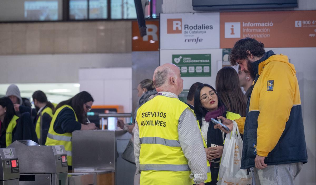 Usuarios de la red de trenes de Rodalies de Renfe en la estación de Barcelona Sants buscando información durante una mañana con incidencias y retrasos pero sin interrupción del servicio.