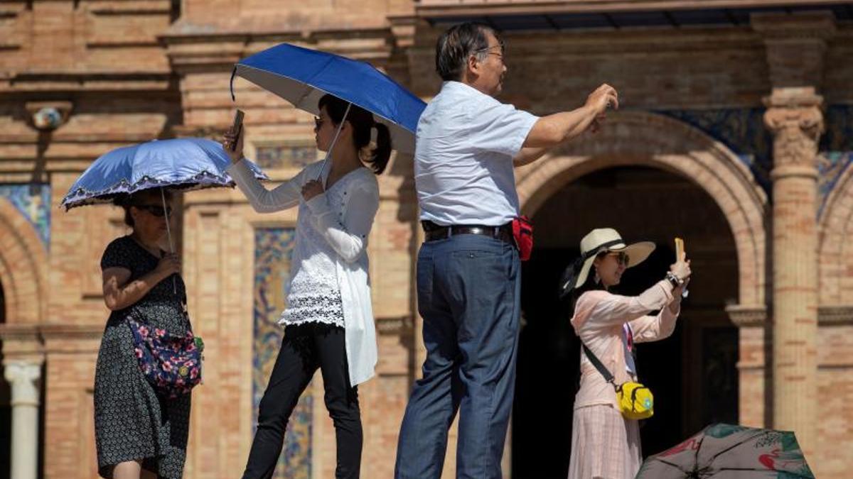 Unos turistas asiáticos toman fotografías en la Plaza de España de Sevilla.