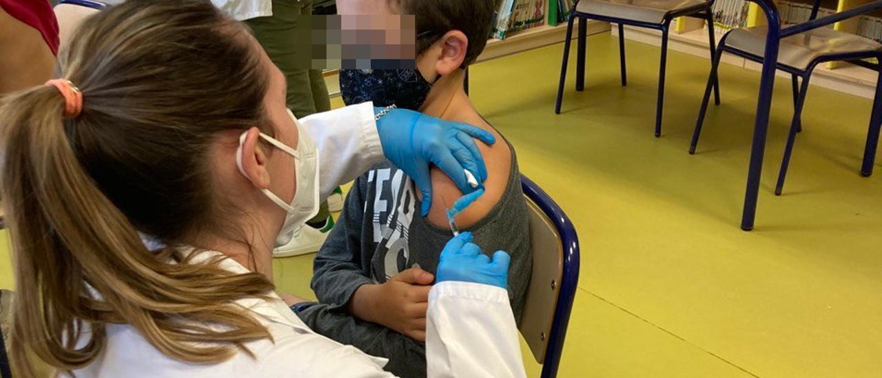 Un infermera administra una vacuna a un xiquet en un col·legi