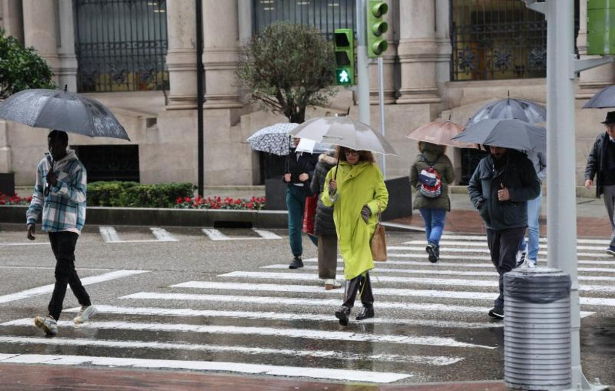 Efectos de la borrasca Joseph en Vigo. Peatones cruzando por un paso de cebra con paraguas.