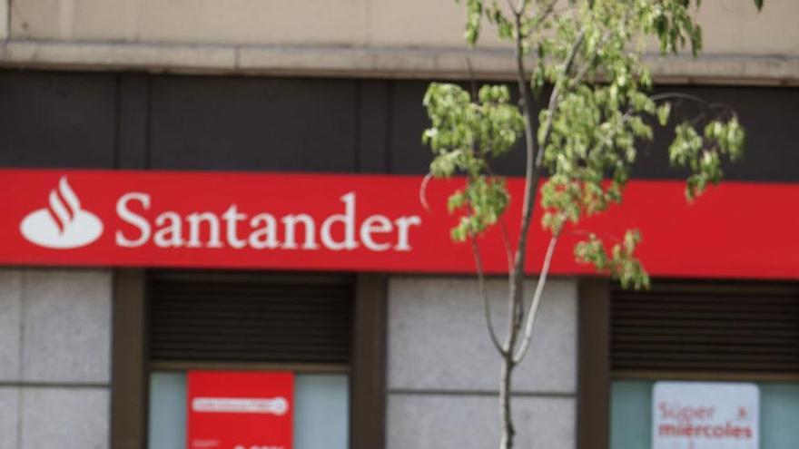 Una mujer sentada frente a una sucursal bancaria en Málaga capital.