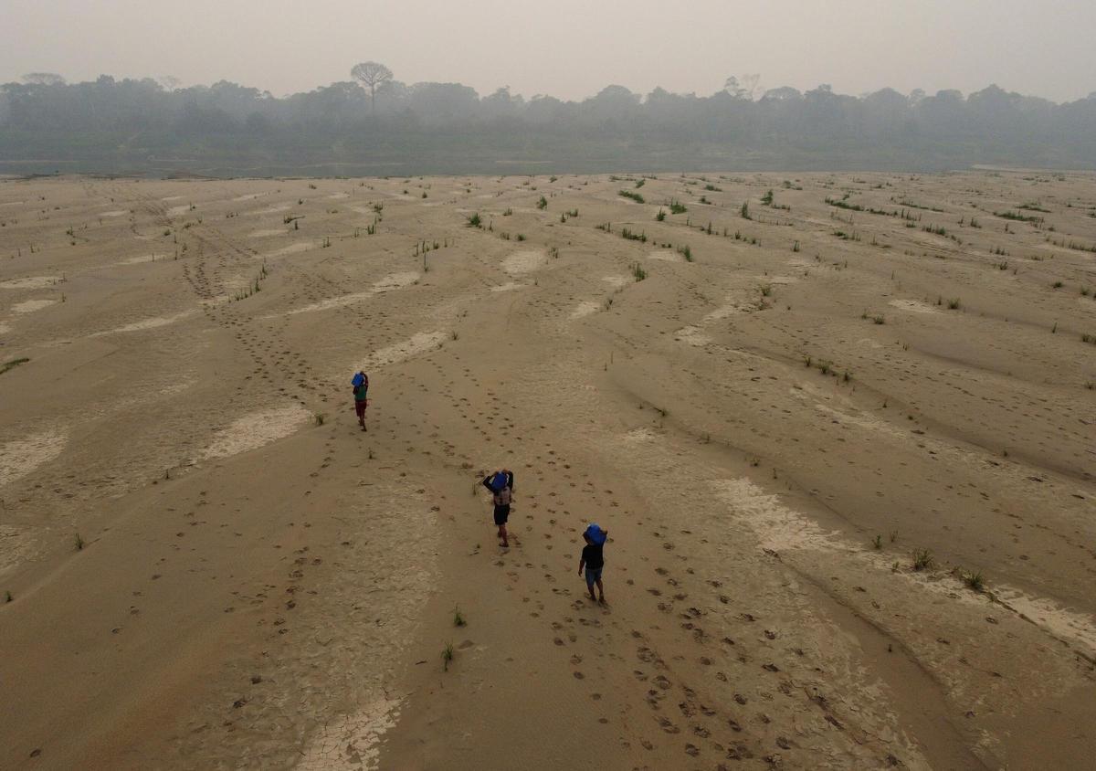 Residentes de Brasil cruzando el cauce seco de un afluente del Amazonas y transportando agua potable