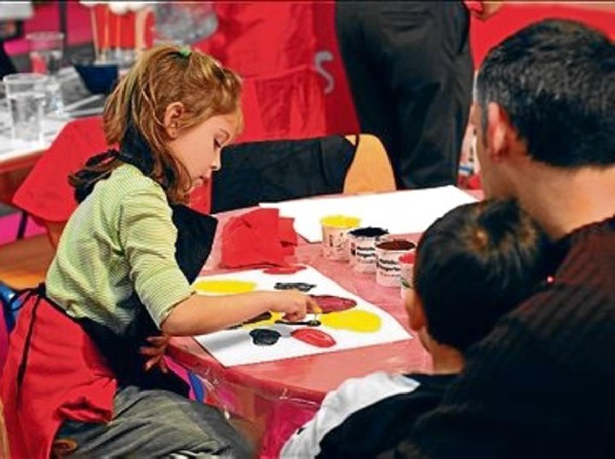 Una niña disfruta pintando con los dedos, en un salón anterior.