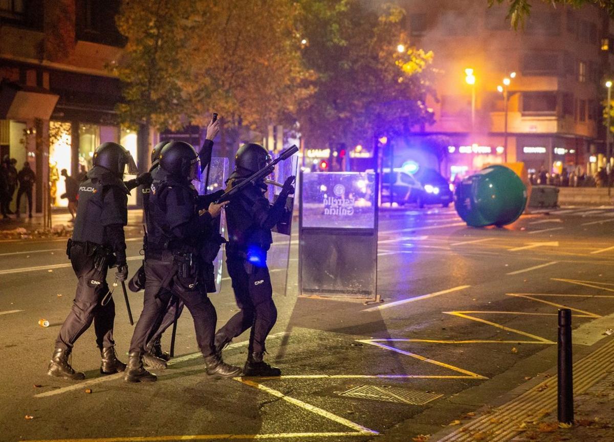 GRAF2036. LOGROÑO, 31/10/2020.- Unos 150 radicales, muchos de ellos jóvenes, han protagonizado esta tarde-noche disturbios en el centro de Logroño, donde han cruzado y quemado contenedores, han tirado piedras y botellas de crisital a la Policía y han cortado el tráfico en las cercanías del Ejecutivo riojano y de la Delegación del Gobierno en La Rioja. En la imagen, agentes antidisturbios intentan controlar la zona. EFE/Raquel Manzanares