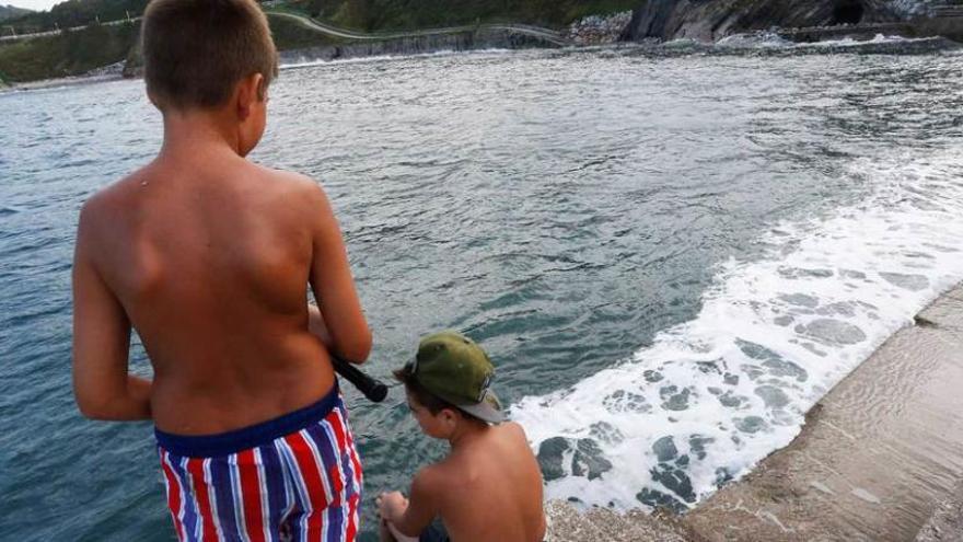 Dos jóvenes bañistas, ayer, en la playa de Arnao (Castrillón), durante la pleamar de las seis de la tarde.