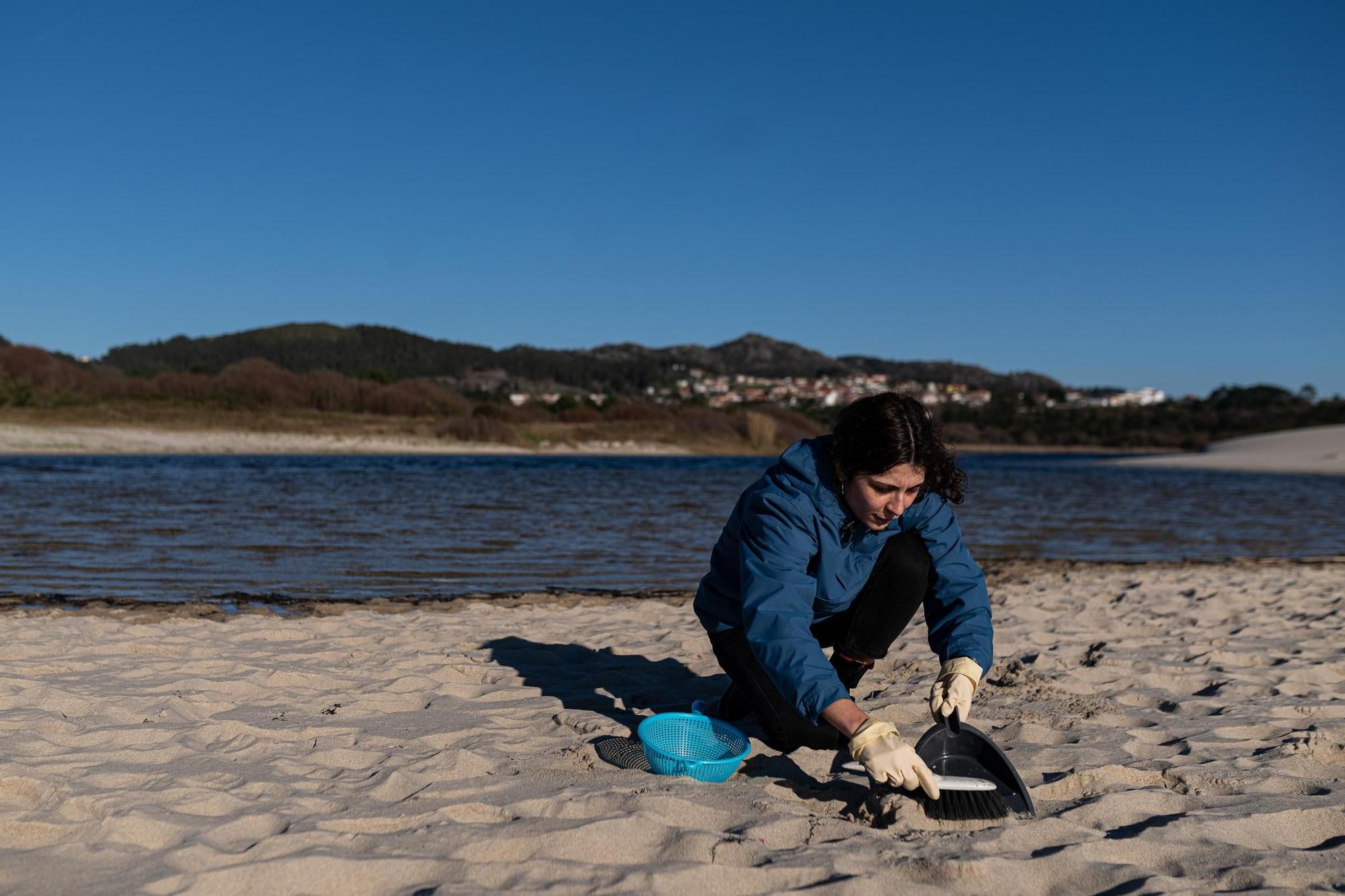 Una voluntaria recoge pellets en la arena de una playa de A Coruña