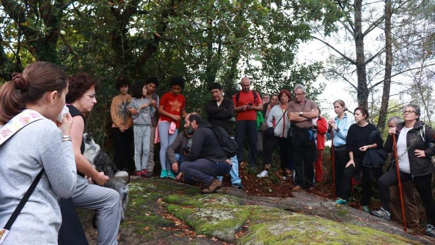 Los participantes en el roteiro de Tirán escuchan las explicaciones sobre yacimientos arqueológicos.// Santos Álvarez