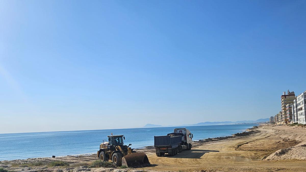 La maquinaria deposita arena en una de las zonas afectadas por el temporal en Tavernes de la Valldigna.