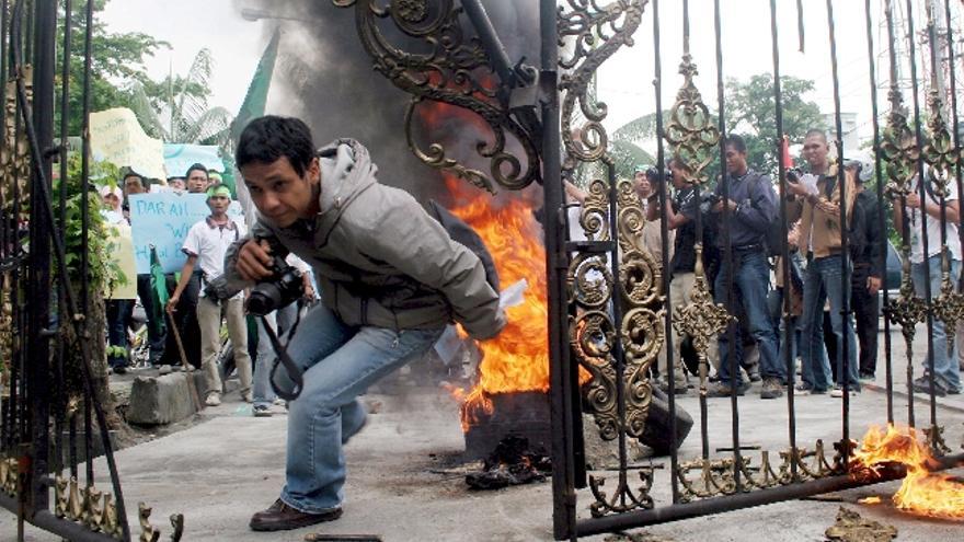 Un fotógrafo indonesio se aleja corriendo del lugar mientras varios manifestantes queman neumáticos a las puertas del consulado holandés durante una manifestación en Medan, Sumatra Norte (Indonesia) .