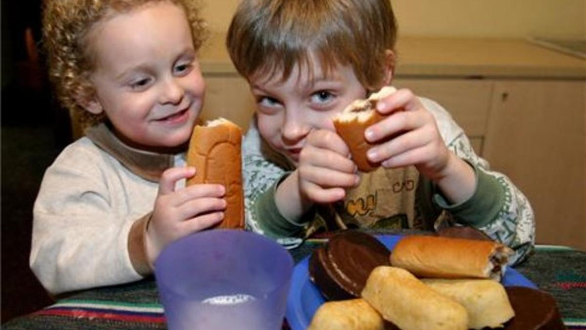 Unos niños ingieren bollería.