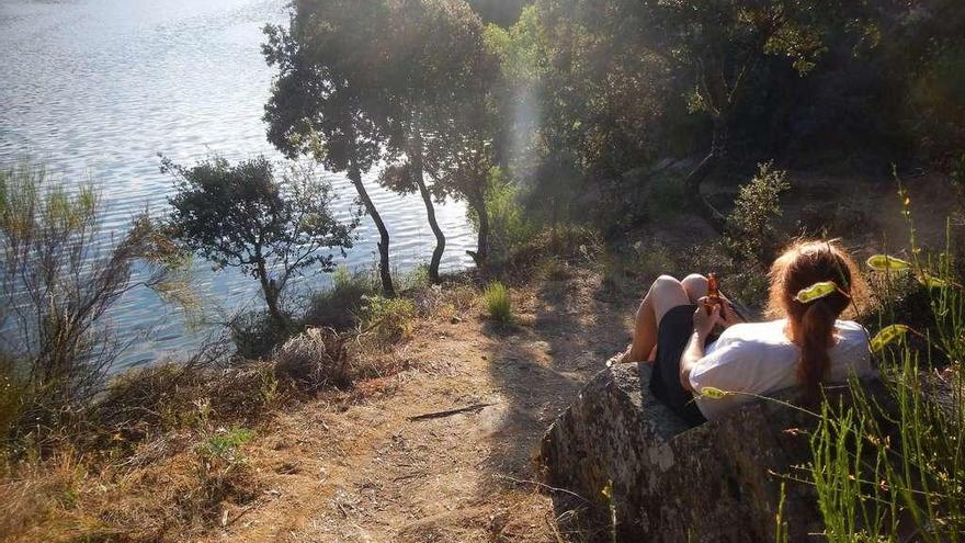 Una joven disfruta del paisaje del Duero sentada en el sillón del barquero.