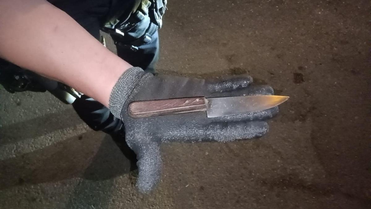 Un agente de la Policía Local porta el cuchillo intervenido tras una pelea en un bar de Alcúdia.