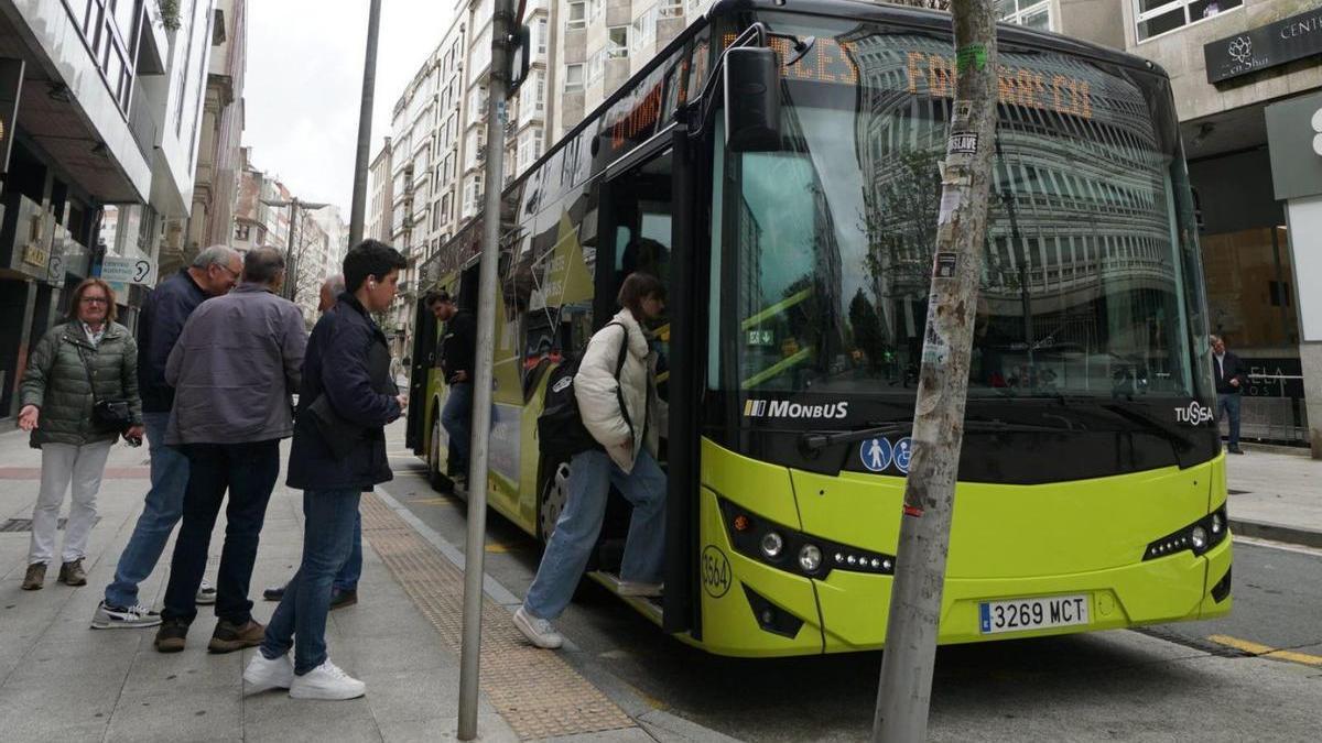 Persoas subindo a un autobús urbano nunha parada do centro da capital galega.