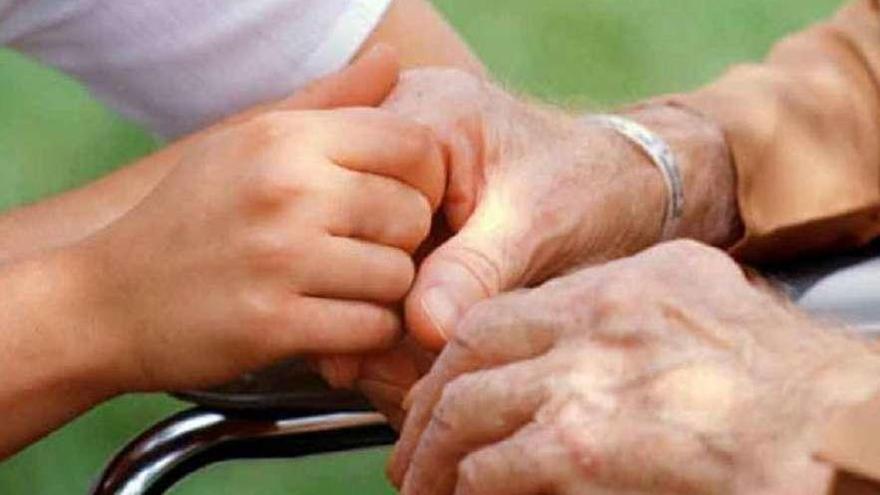Un cuidador sostiene la mano de una persona mayor.